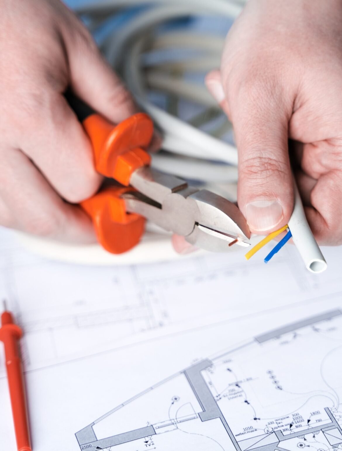 Man repairer making electricity project in house.Repairs planning.Drawing,diagrams,plan of electrification of apartment,building.Devices,accessories,voltmeter,wires,screwdriver,pliers and tape measure